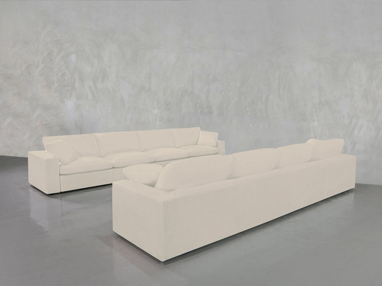 The 4-4 Sofa Set, featuring two large, modern white sofas with plush cushions, is arranged in an L-shape on a shiny gray floor against a light gray textured wall.