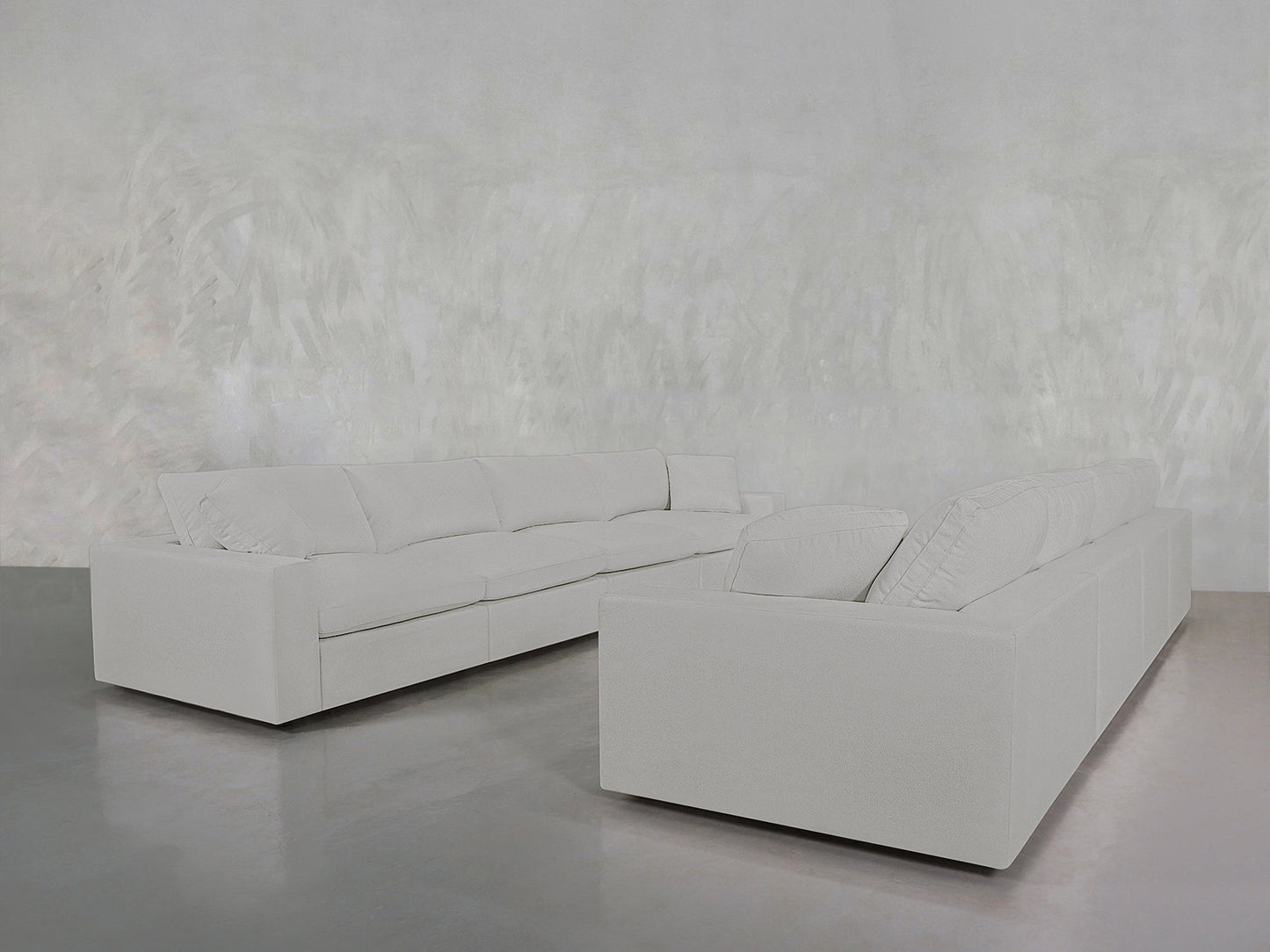 The 4-4 Sofa Set, in a large light gray L-shape, rests on a shiny gray floor in a minimalist room with textured pale gray walls, creating a modern and uncluttered space.