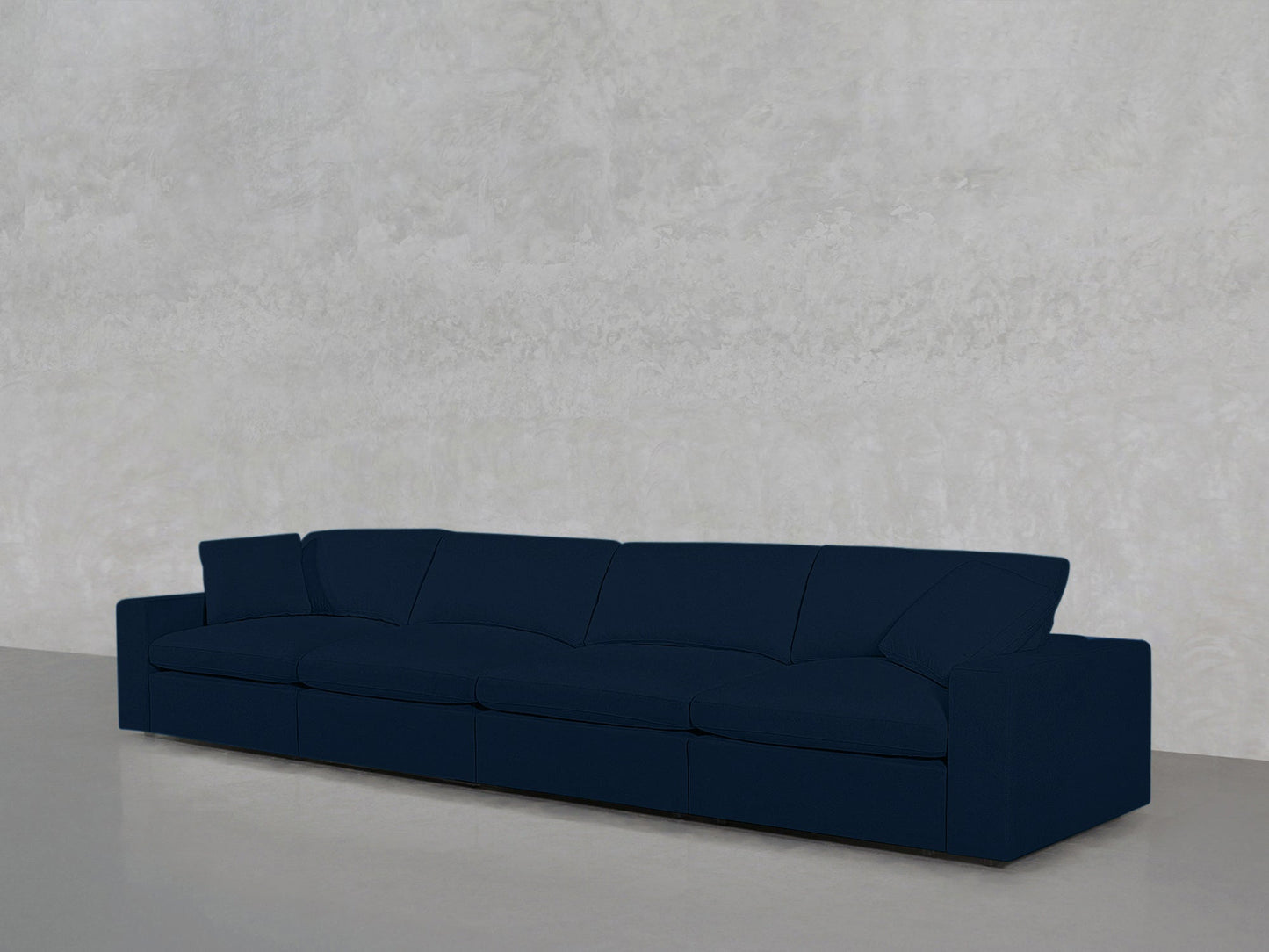 A 4-Seat Modular Sofa with dark blue upholstery and low armrests is placed against a plain, light gray textured wall on a smooth, light-colored floor.