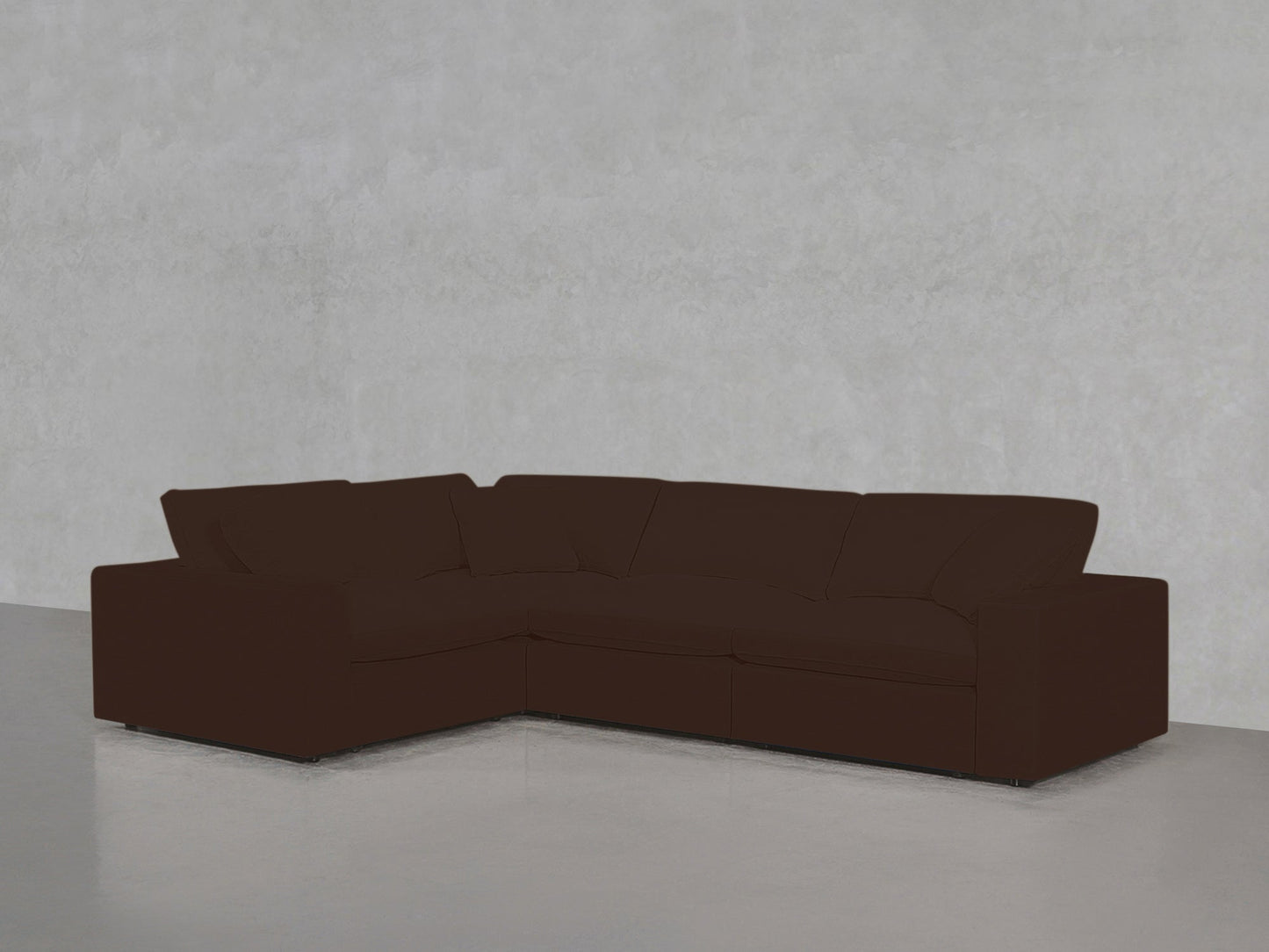 A 4-Seat Modular Corner Sectional in dark brown is positioned against a light gray textured wall on a smooth, light gray floor.