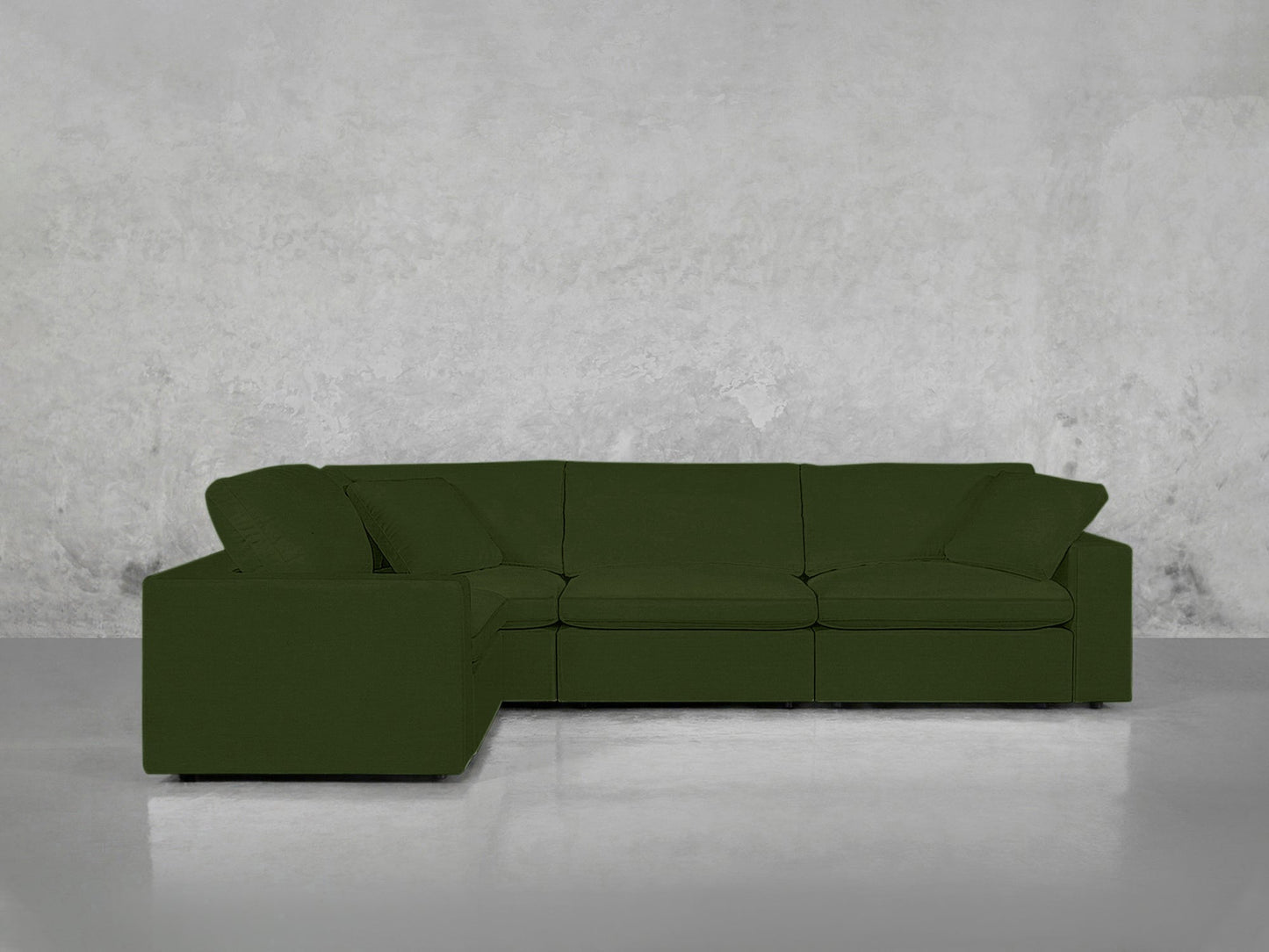 A 4-Seat Modular Corner Sectional with a modern green design and clean lines is placed against a plain, light gray textured wall on a smooth, reflective floor.