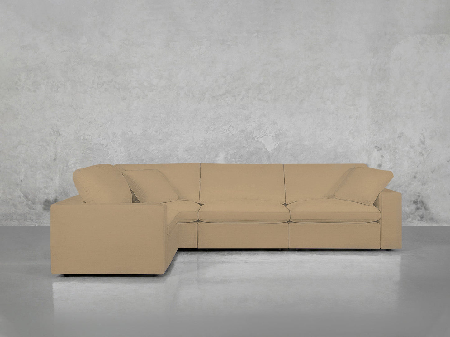 A 4-Seat Modular Corner Sectional with clean lines and plush cushions is placed on a polished gray floor against a textured light gray wall.