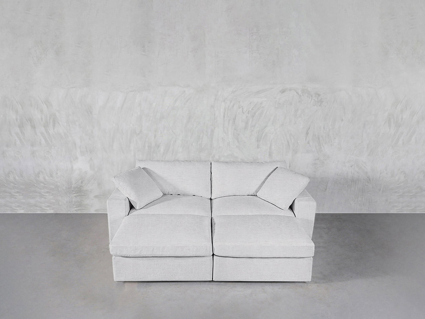 A modern light gray 4-Seat Modular Daybed sits against a textured light gray wall on a smooth gray floor.
