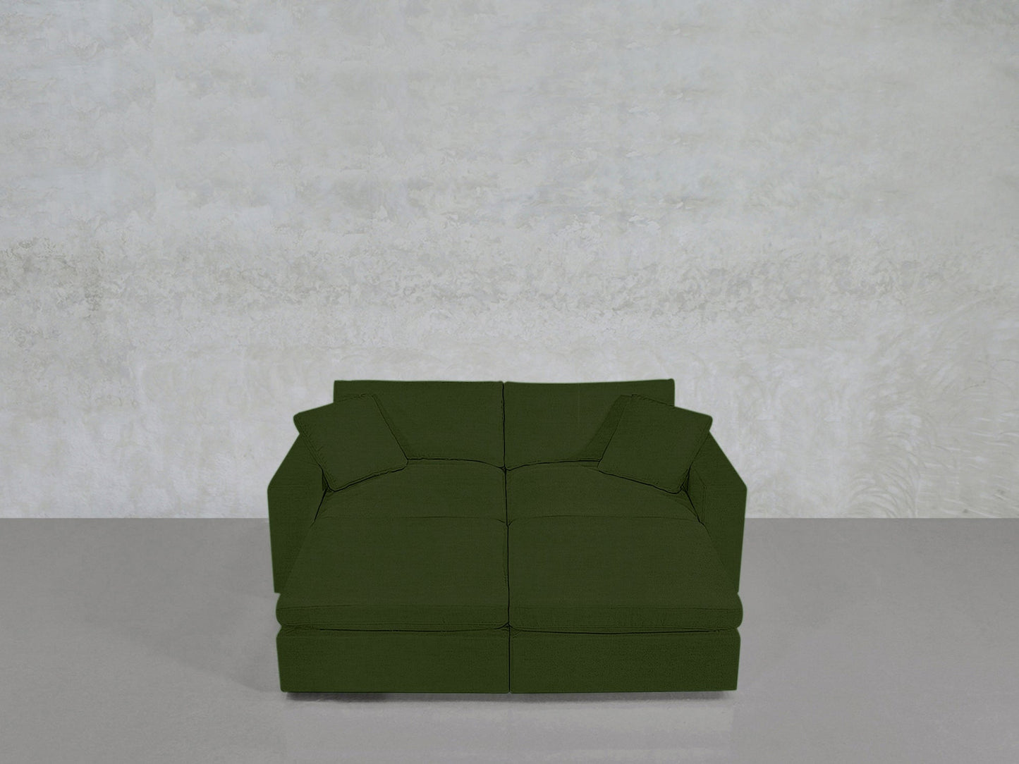 A green, modern 4-Seat Modular Daybed with two matching cushions sits against a light textured wall on a smooth gray floor.