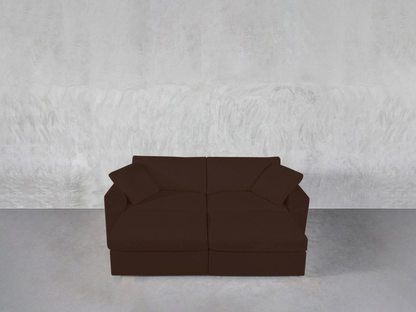 A 4-Seat Modular Daybed with two matching cushions sits against a light gray textured wall on a polished concrete floor.
