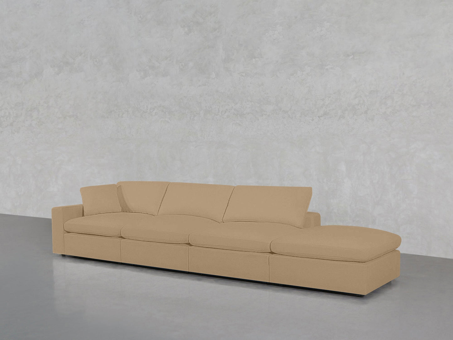 The 4-Seat Modular Lounger Sofa, featuring a modern beige design with a low backrest and wide cushions, is set against a light gray textured wall on a smooth gray floor.