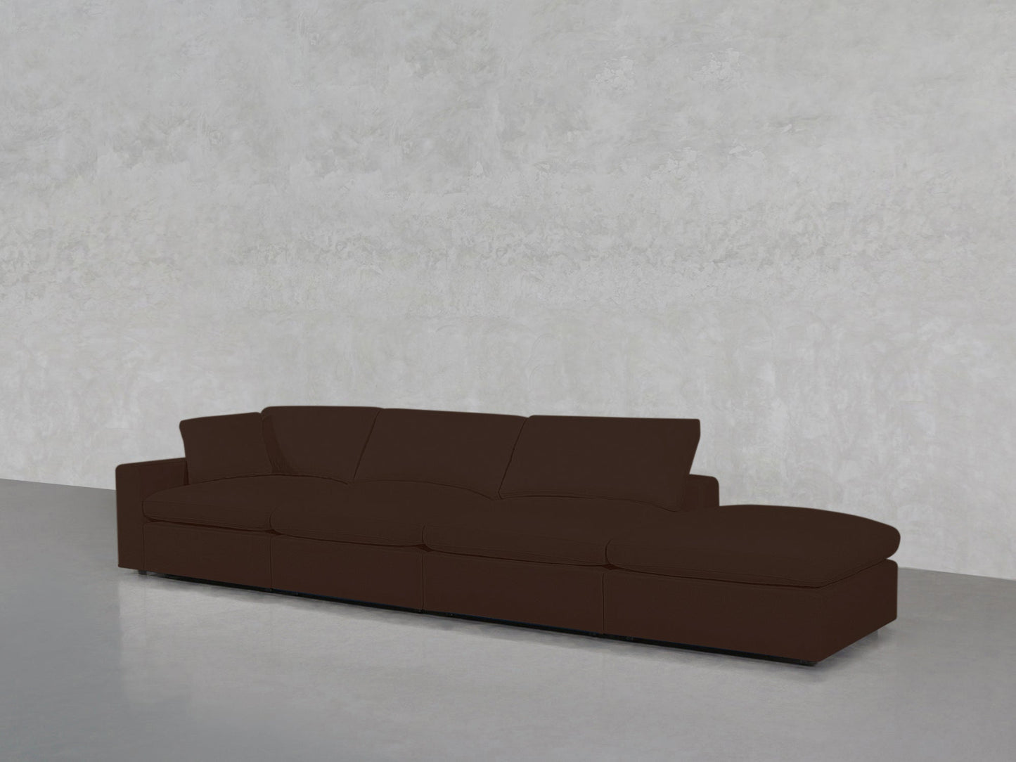 A 4-Seat Modular Lounger Sofa in modern dark brown with wide seats and plush cushions is placed against a textured light gray wall and a smooth, light gray floor.