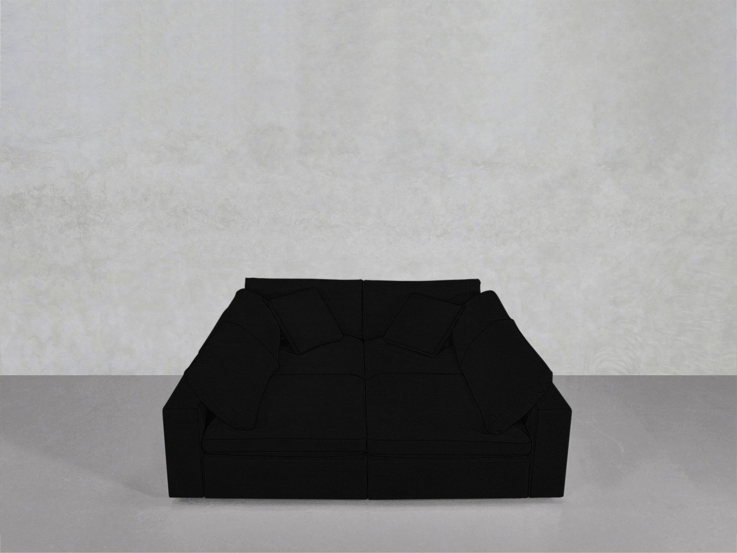 The 4-Seat Modular Pit, a large modern black sofa with four matching cushions, sits on a grey floor against a plain light grey wall.
