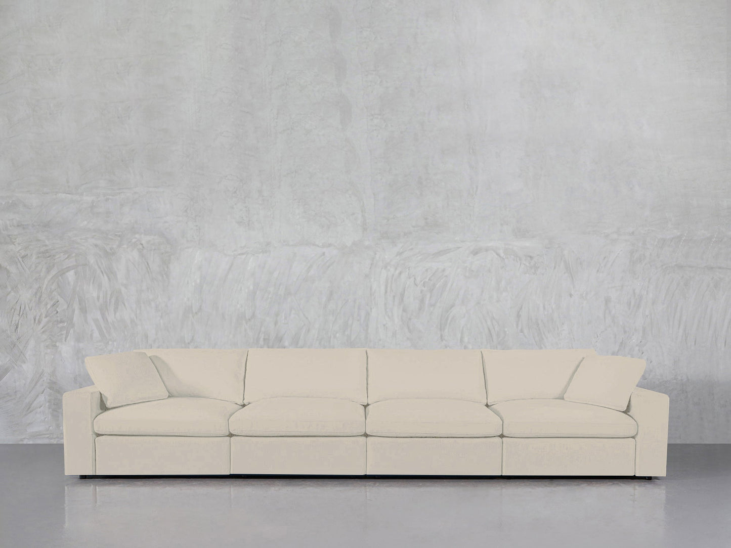 A modern cream-colored 4-Seat Modular Sofa stands against a textured light gray wall on a polished, reflective floor.