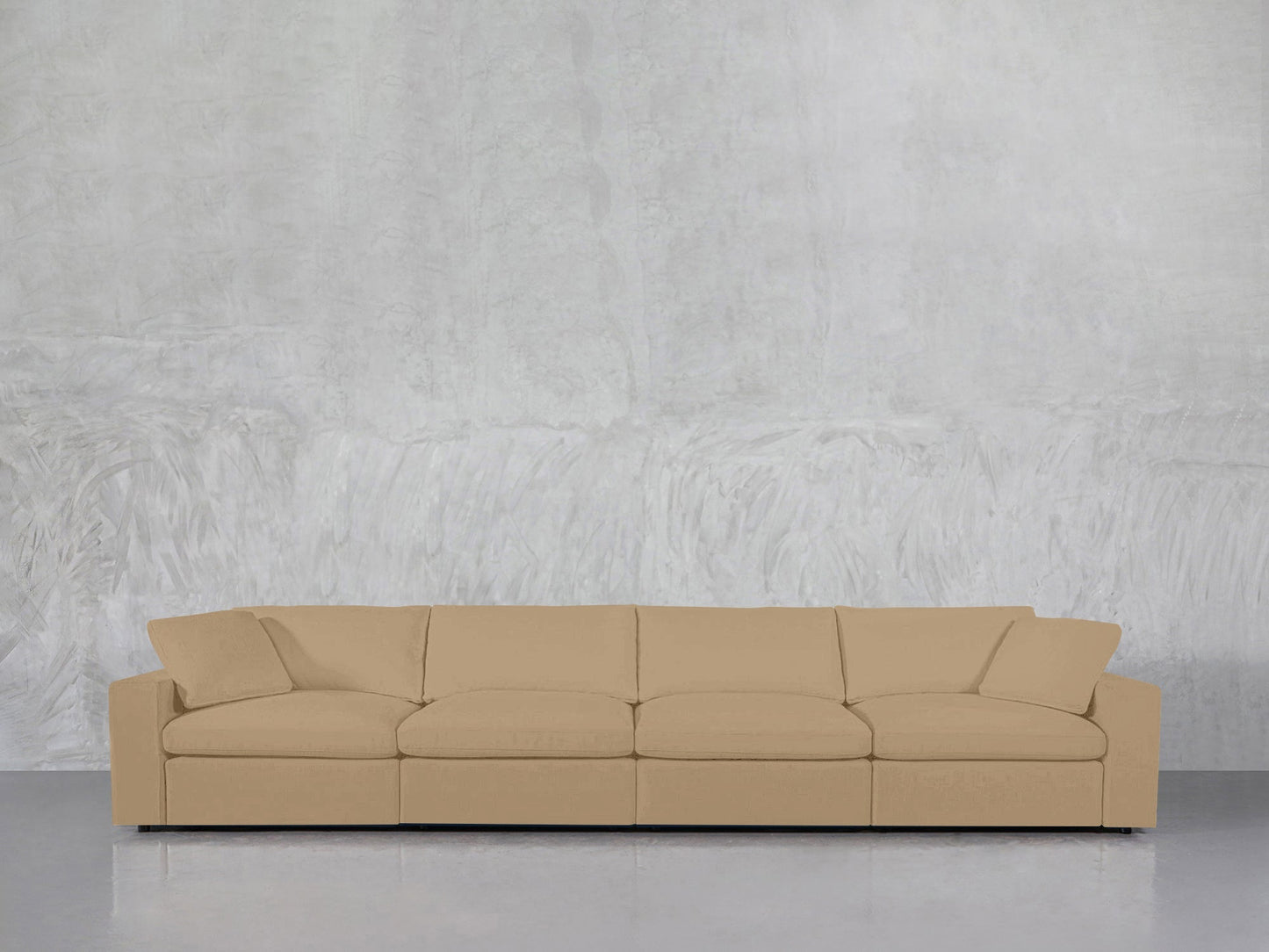 A spacious beige 4-Seat Modular Sofa with angled armrests is placed in front of a textured light gray wall on a glossy floor.