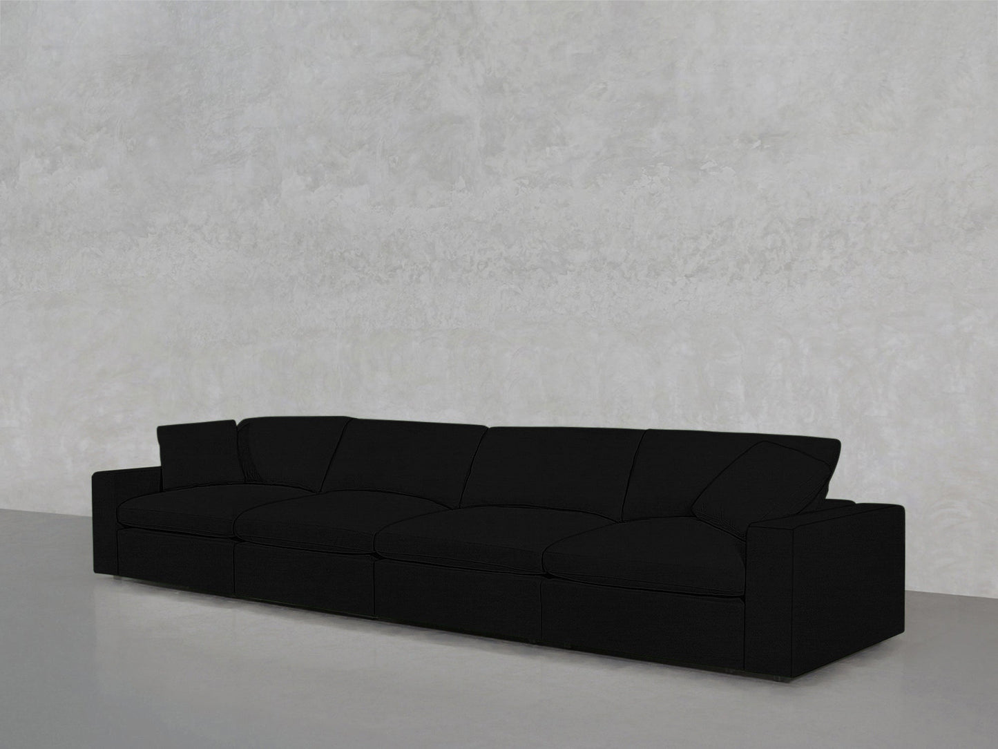 The 4-Seat Modular Sofa, featuring a modern black design and clean lines, is placed against a light gray textured wall on a smooth gray floor.
