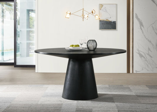 A modern dining area with the Jasper - Wide Contemporary Round Dining Table, set with two glasses, a plate of green apples, and a decorative vase. A geometric chandelier hangs above, with abstract art and a large window in the background.