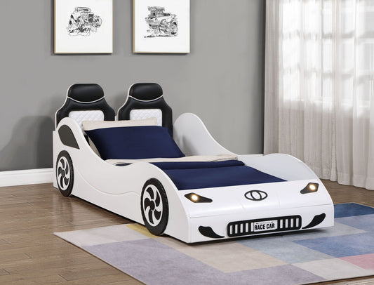 The Colen - Twin Car Bed With LED is a modern children’s bed shaped like a white race car with black detailing, two car seat-style headrests, and a “RACE CAR” plate, shown on a wooden floor near a window and wall art.