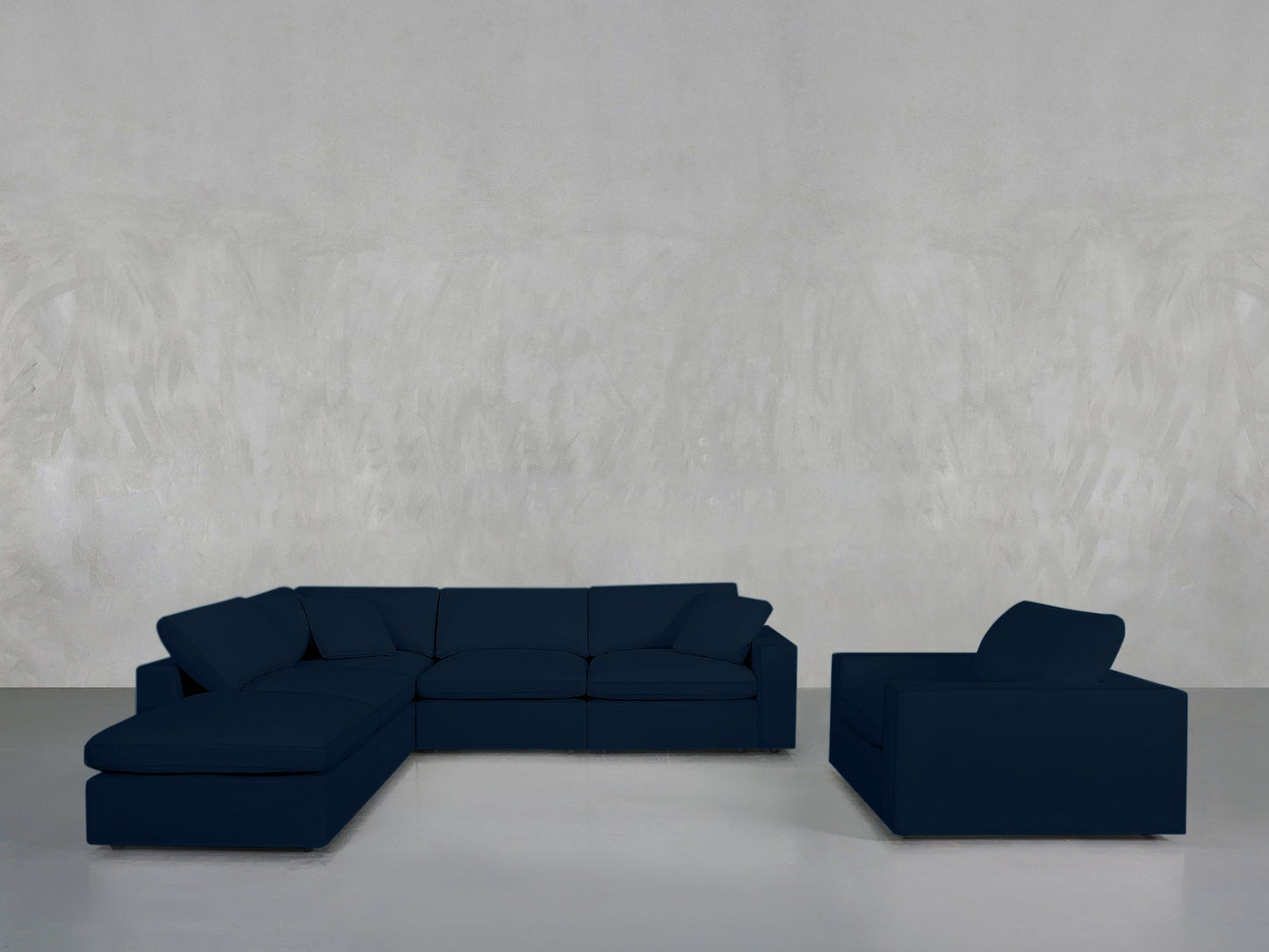 The 5-1 Sectional & Armchair Set in dark blue is arranged on a light grey floor against a textured light grey wall, creating a minimalist ambiance.