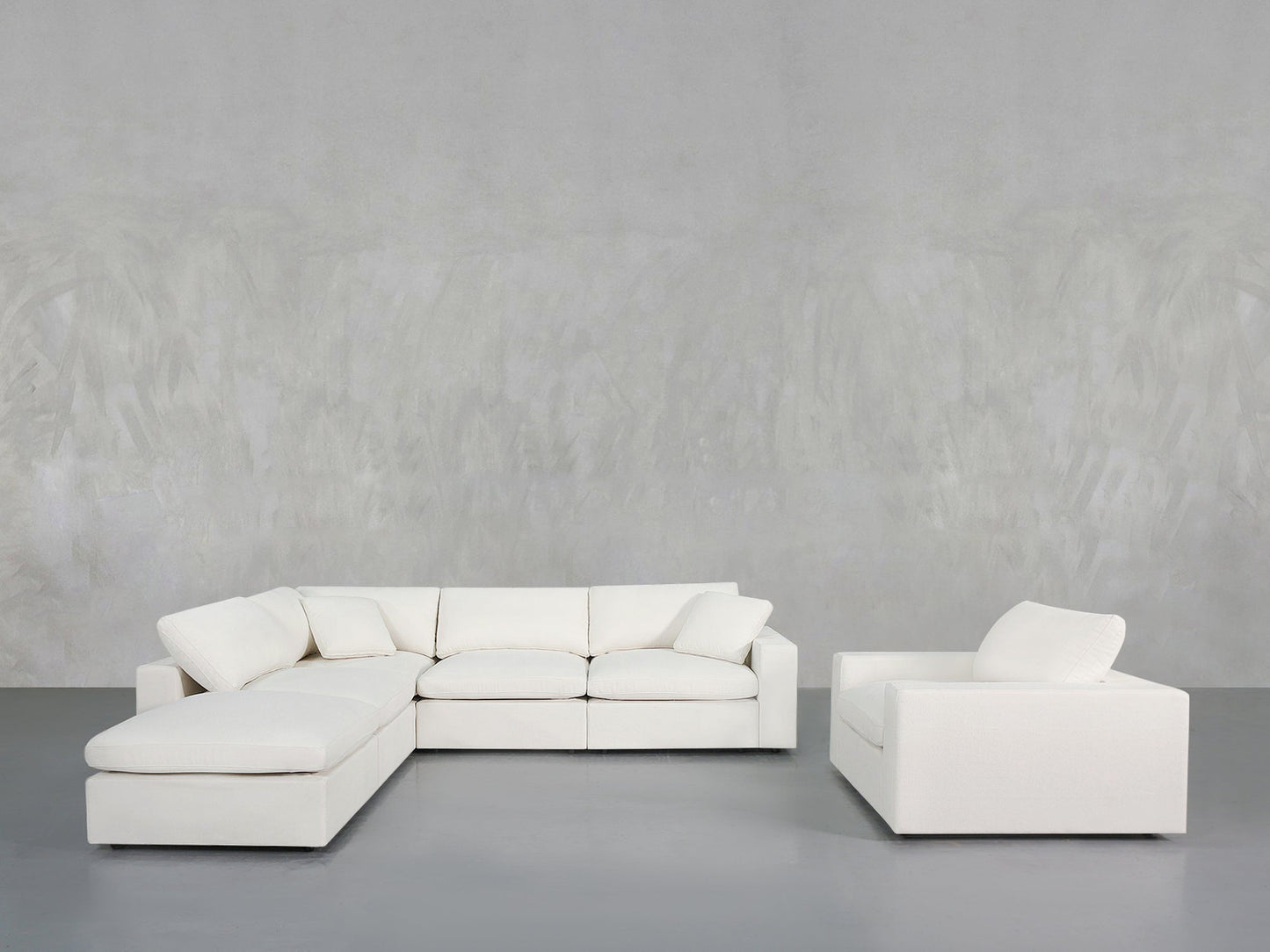 A modern, minimalist living room featuring the 5-1 Sectional & Armchair Set in white, arranged against a light gray textured wall and gray floor.