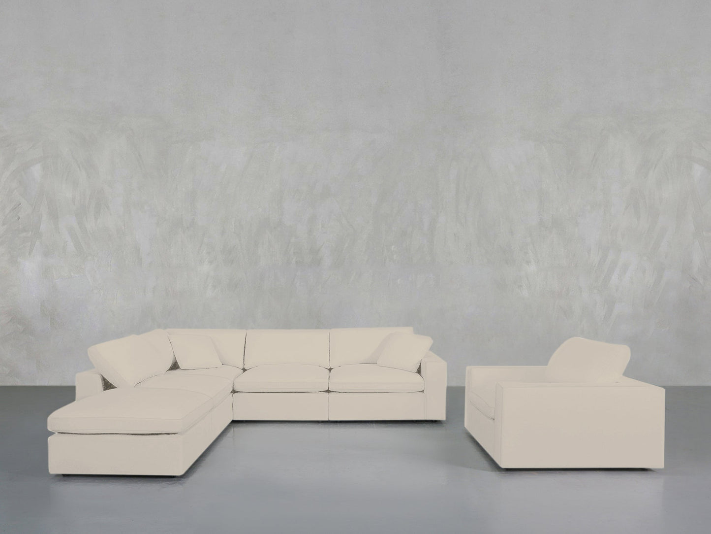 A minimalist room with a light gray wall showcases the 5-1 Sectional & Armchair Set in cream, positioned on a smooth gray floor.