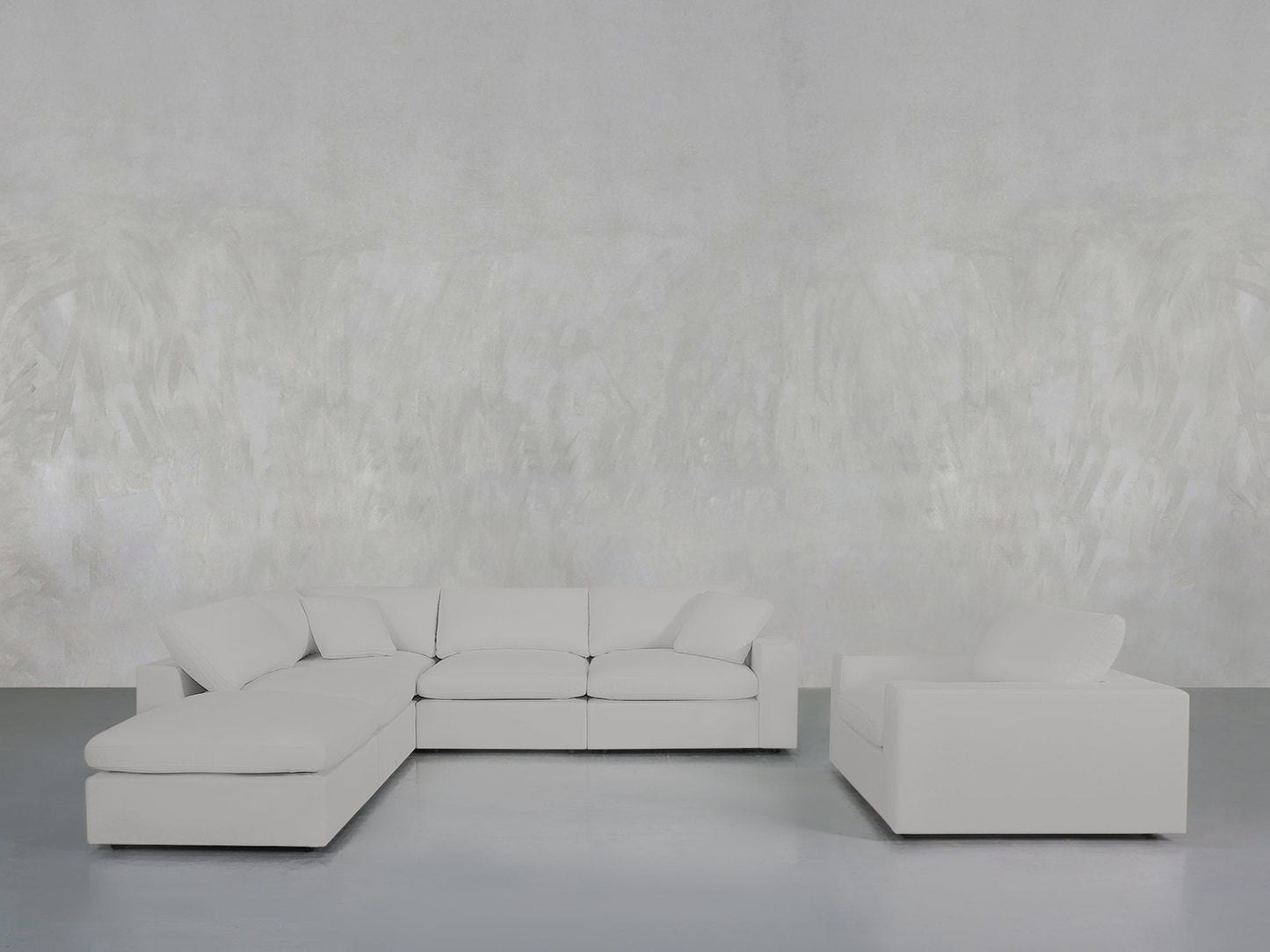 A minimalist living room featuring the 5-1 Sectional & Armchair Set in light gray, placed against a pale textured wall and smooth gray floor.