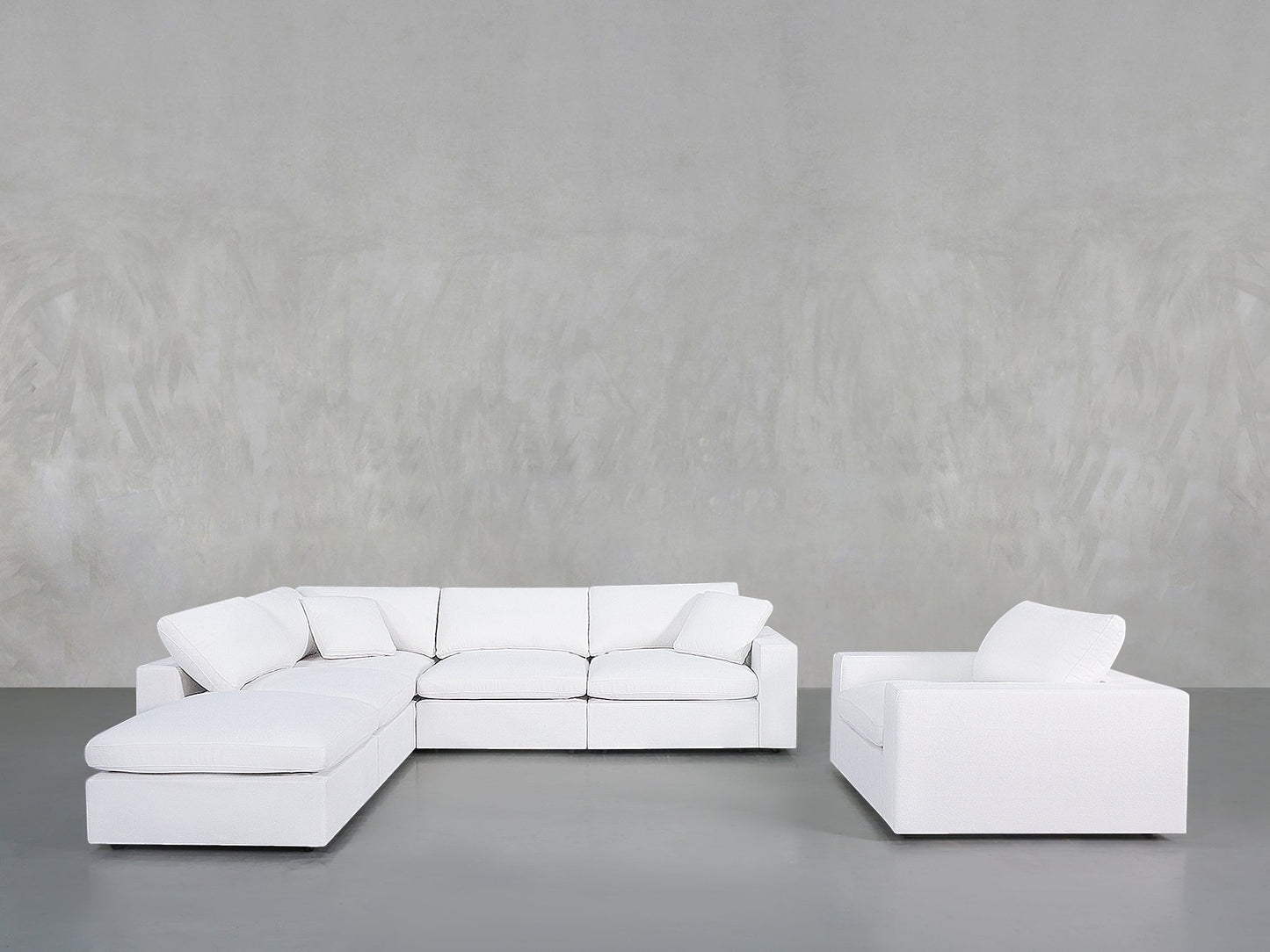 A minimalist living room with the 5-1 Sectional & Armchair Set in white, set against a light gray textured wall and a smooth gray floor.