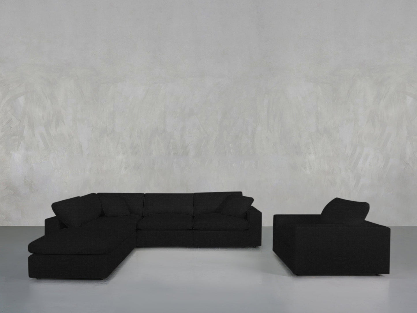 A modern living room with the 5-1 Sectional & Armchair Set in black, set against a light gray textured wall and a smooth gray floor.