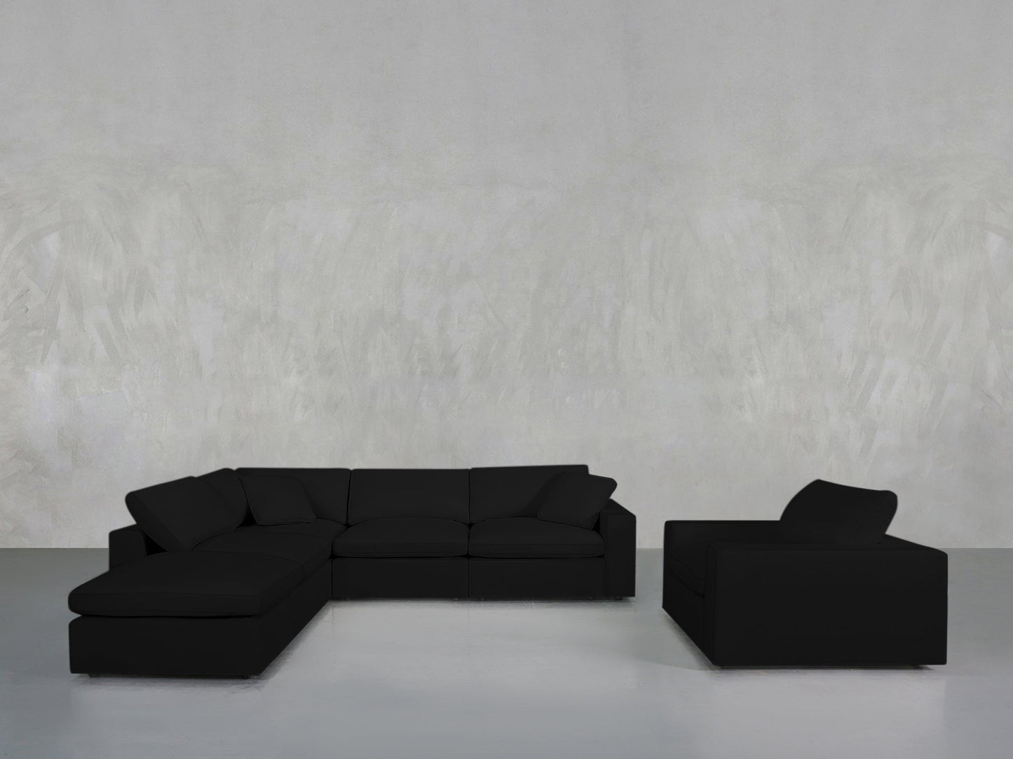 A modern living room showcases the 5-1 Sectional & Armchair Set in black, arranged against a plain light gray textured wall and a minimalist gray floor.