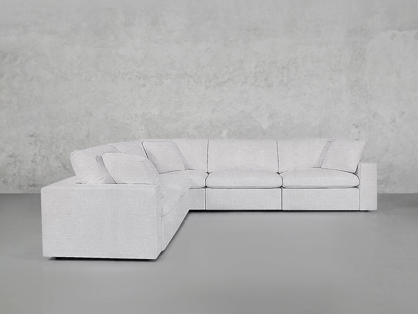 A 5-Seat Modular Corner Sectional with clean lines and plush cushions sits against a plain, textured gray wall and floor.