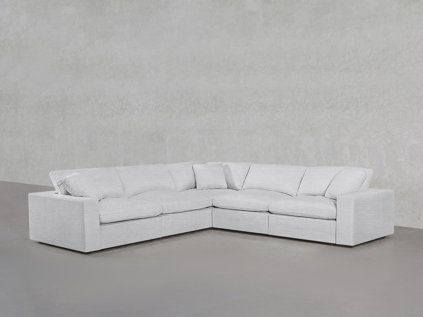 A 5-Seat Modular Corner Sectional in modern light gray with plush cushions sits against a textured light gray wall and a smooth gray floor.