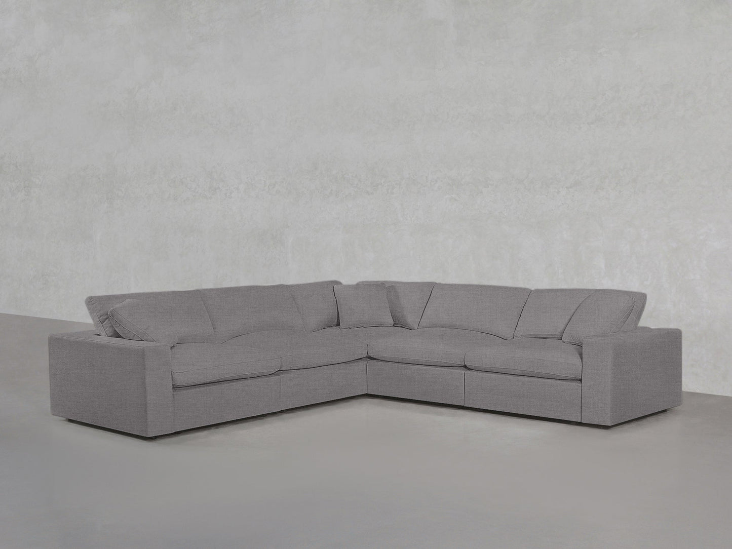 The 5-Seat Modular Corner Sectional features plush cushions and clean lines, styled in gray against a light gray textured wall and floor for a minimalist look.