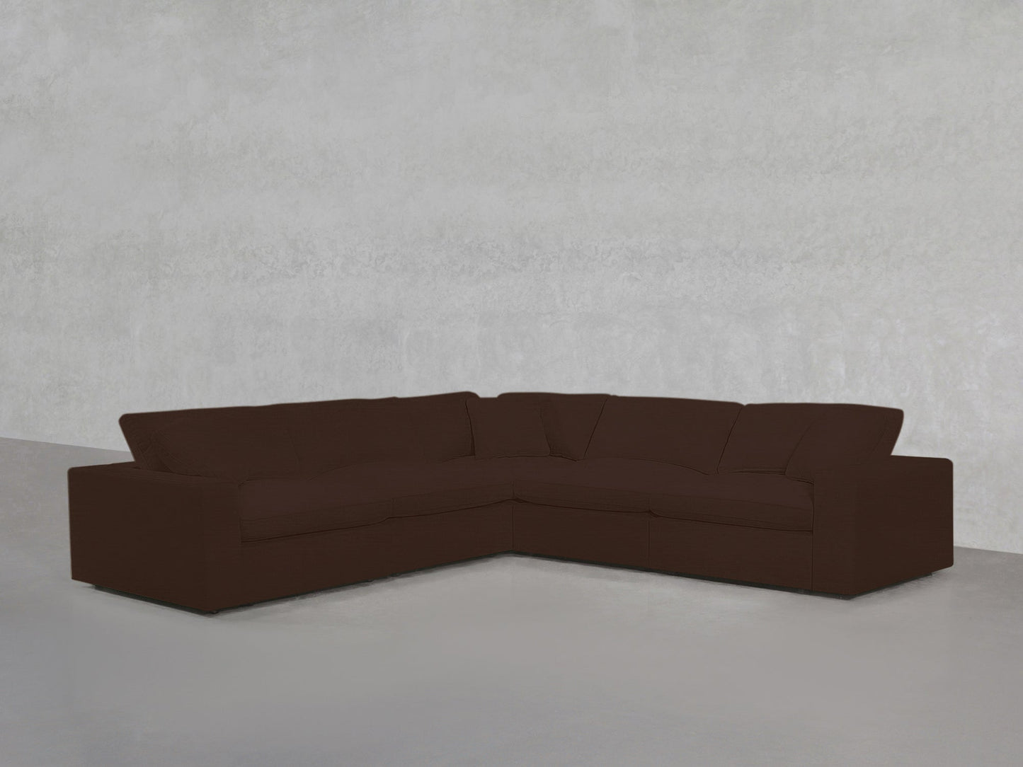 A 5-Seat Modular Corner Sectional in dark brown with plush cushions is arranged in an L-shape against a plain, light gray wall and floor.