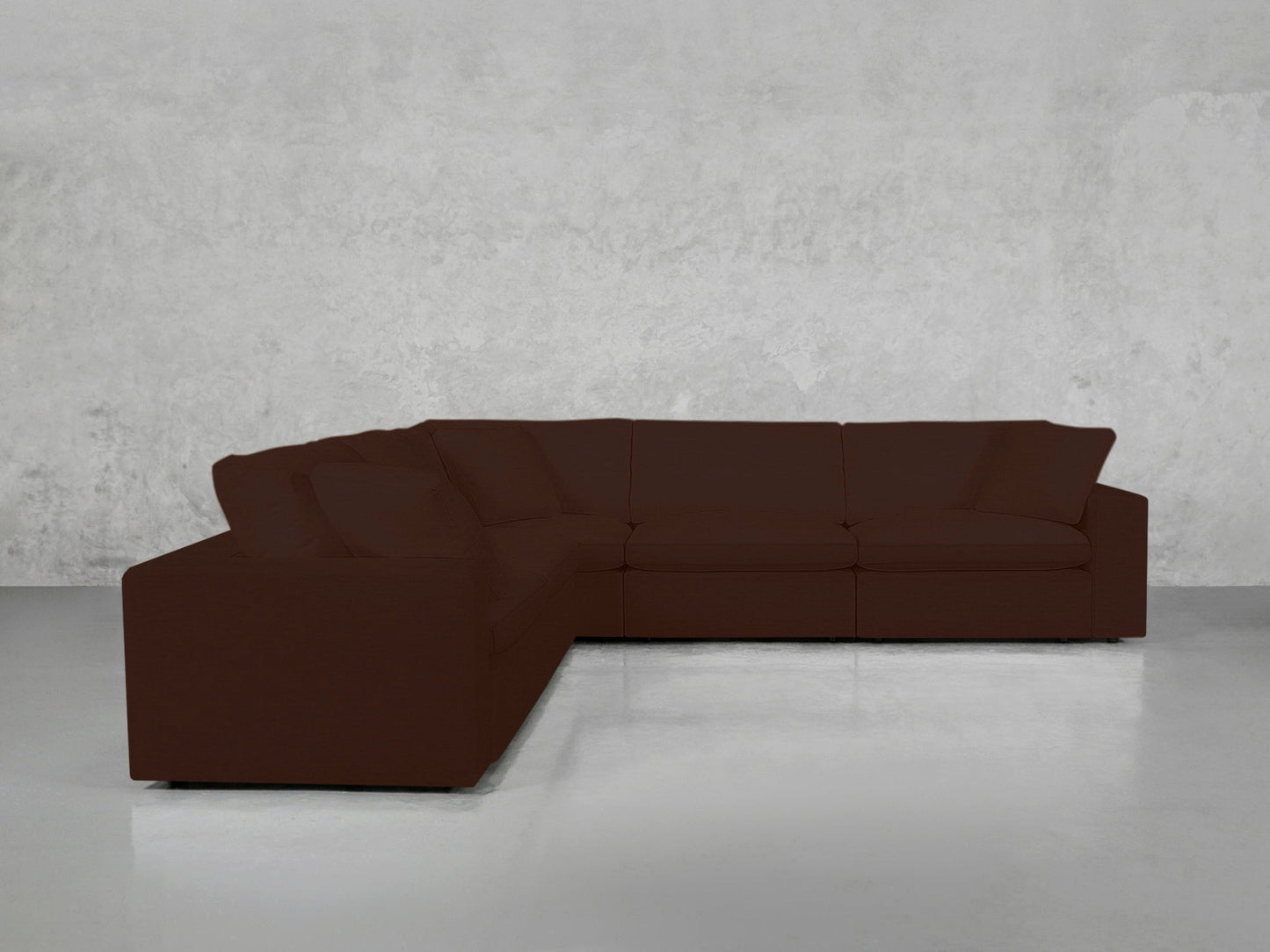 A 5-Seat Modular Corner Sectional in dark brown with cushions is arranged in a minimalist room featuring light gray concrete walls and a glossy white floor.