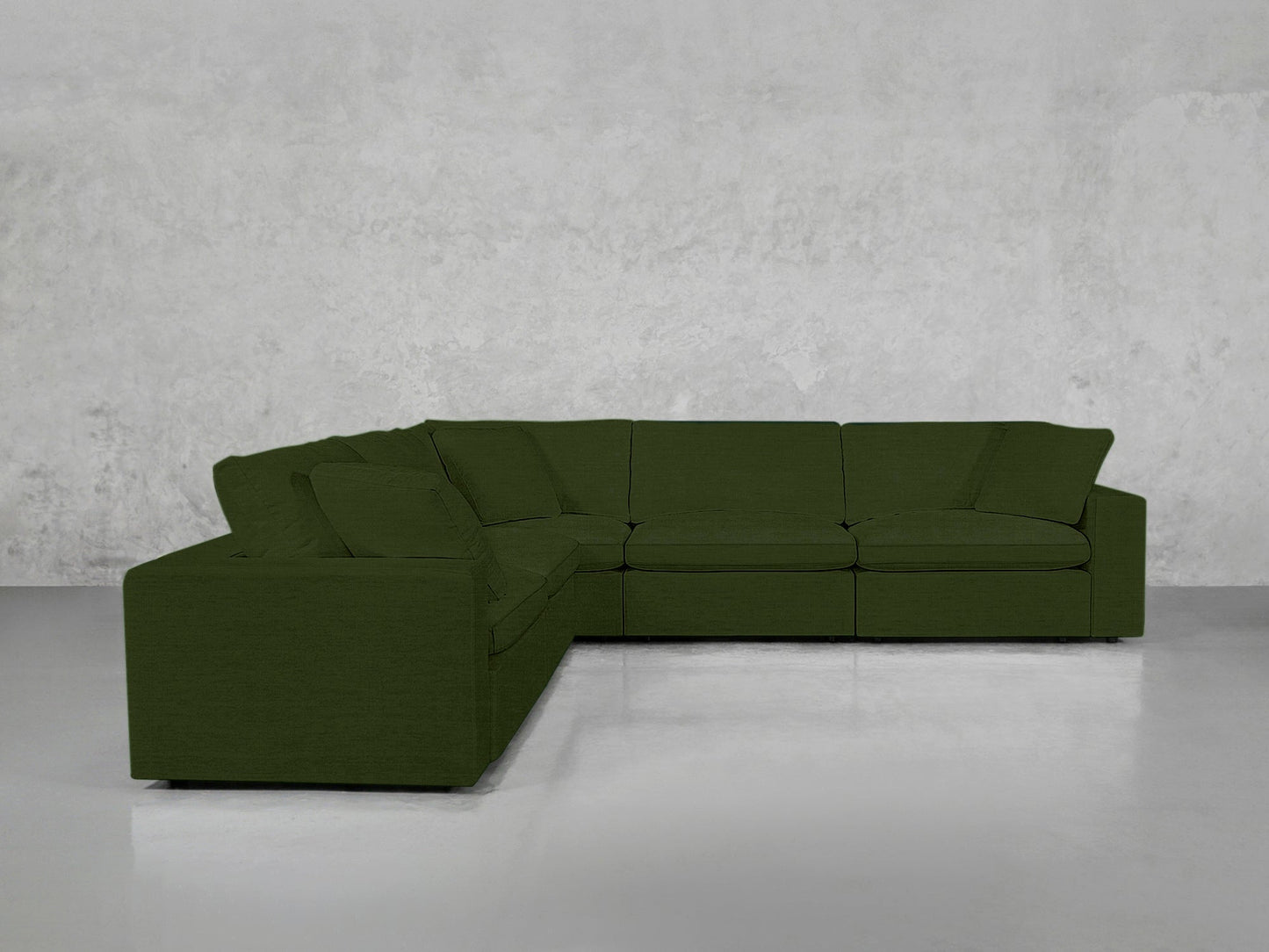A 5-Seat Modular Corner Sectional in dark green with clean lines is set against a plain light gray wall in a minimalist room with a smooth, light floor.