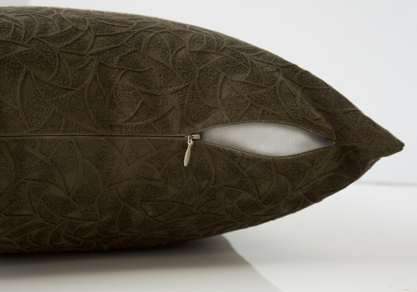 A close-up of a dark brown modern square decorative throw pillow with a subtle leaf pattern and a partially open zipper, revealing the white hypoallergenic insert included.