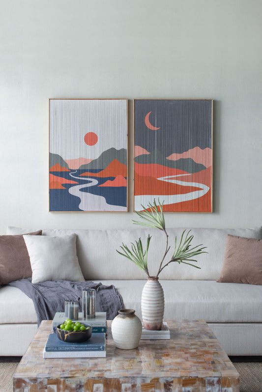 A modern living room with a white sofa, neutral cushions, and a cozy gray throw. Above, Rectangular Tassel Print Wall Art in multicolor adds flair. A coffee table displays books, vases, and a bowl of green apples.