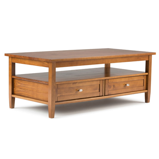 The Warm Shaker Coffee Table in light golden brown features a rectangular design with a lower shelf, two drawers with metal handles, and tapered legs.