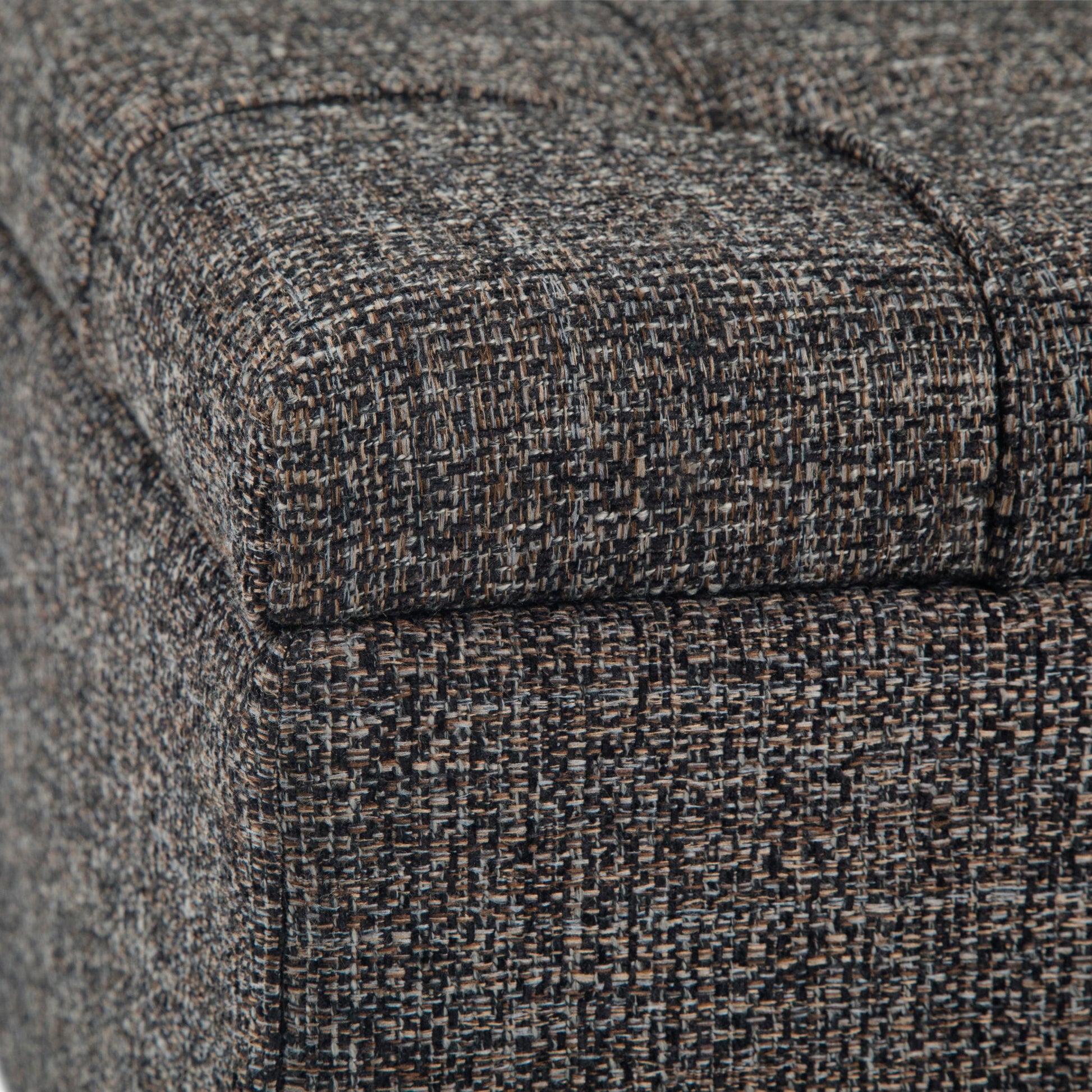 Close-up of the Harrison Upholstered Coffee Table Storage Ottoman, highlighting its tightly woven, textured gray, brown, and black fabric with visible seams and stitching.