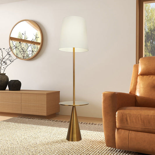 A modern living room with a tan leather armchair, the Celestial gold and white floor lamp with accent table, a wooden sideboard with black vases, a round wall mirror, and a textured rug on light wood flooring.