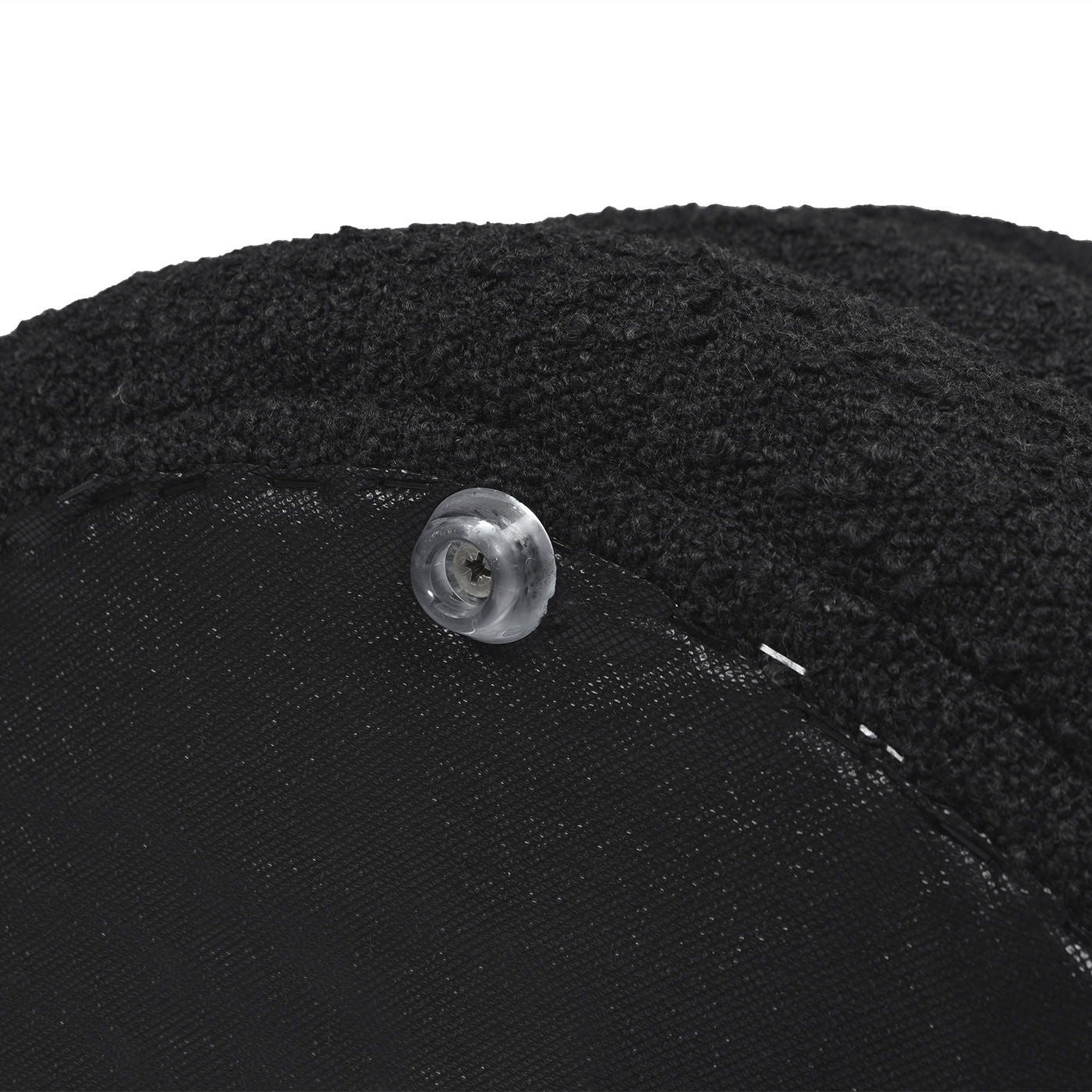 Close-up of the Fuji - Oversized Round Storage Ottoman, featuring black textured fabric and a clear plastic button sewn onto its edge.