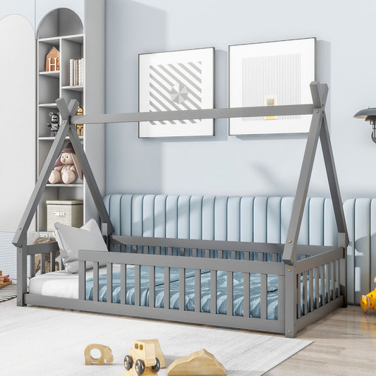 A modern children’s bedroom with a gray Tent-Shaped Floor Bed featuring guardrails and slats, blue padded wall, two framed geometric prints, shelves with toys and books, a round rug, and wooden toys on the floor.