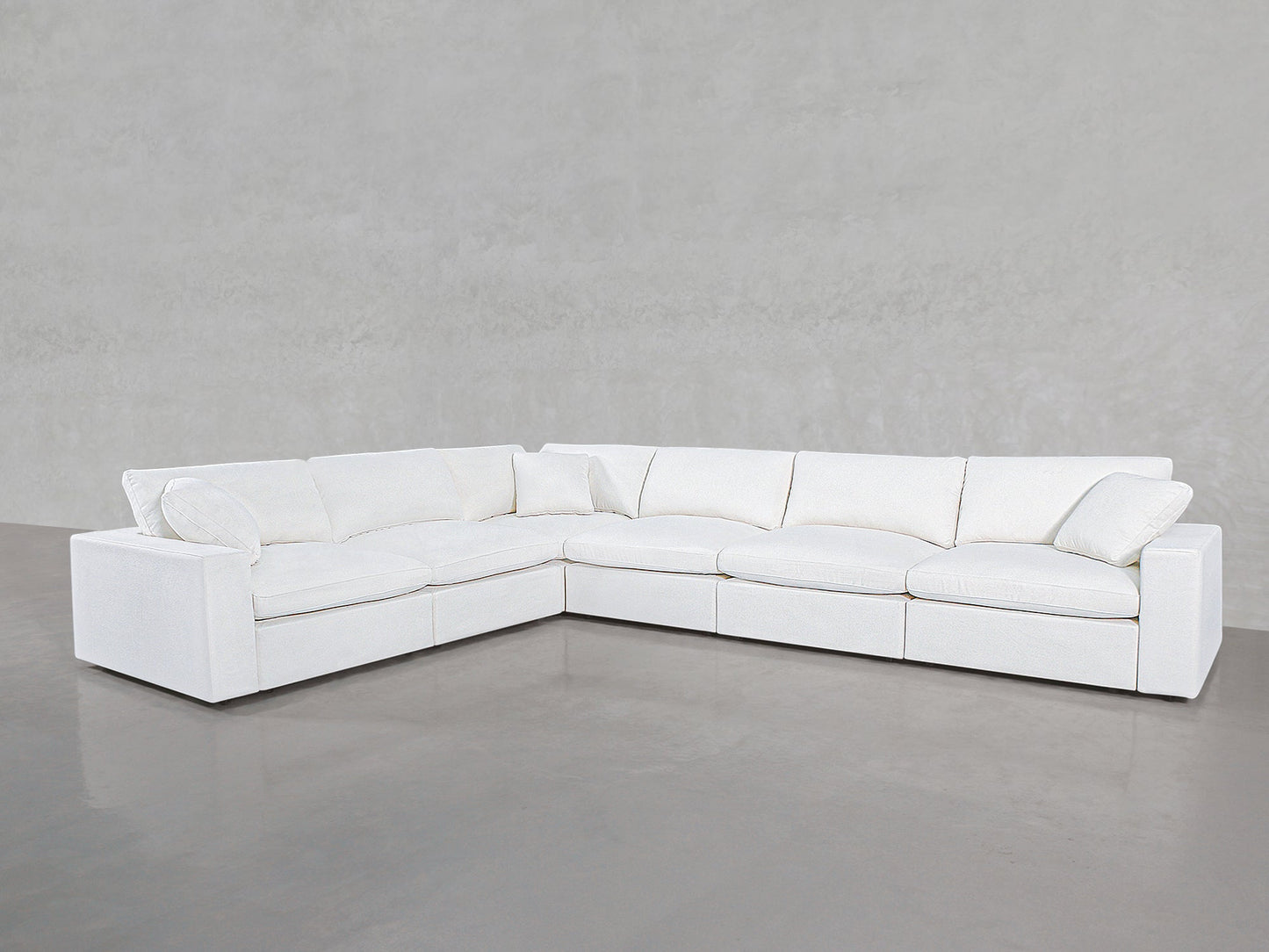 A spacious 6-Seat Modular Corner Sectional with clean lines and plush cushions is arranged in an L-shape against a light gray wall and floor.
