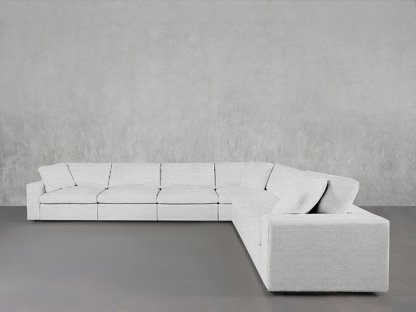 A 6-Seat Modular Corner Sectional in light gray fabric sits against a plain light gray wall on a smooth, dark floor.