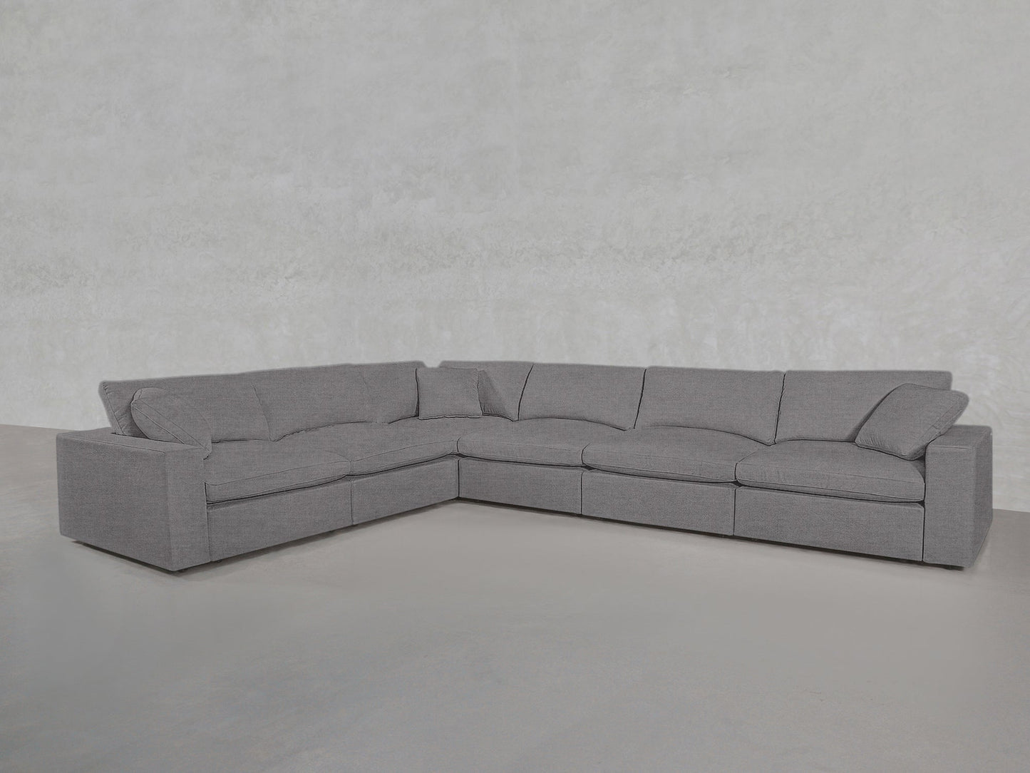The 6-Seat Modular Corner Sectional features plush cushions and armrests in a modern gray L-shaped design, set against a light gray textured wall and smooth floor.
