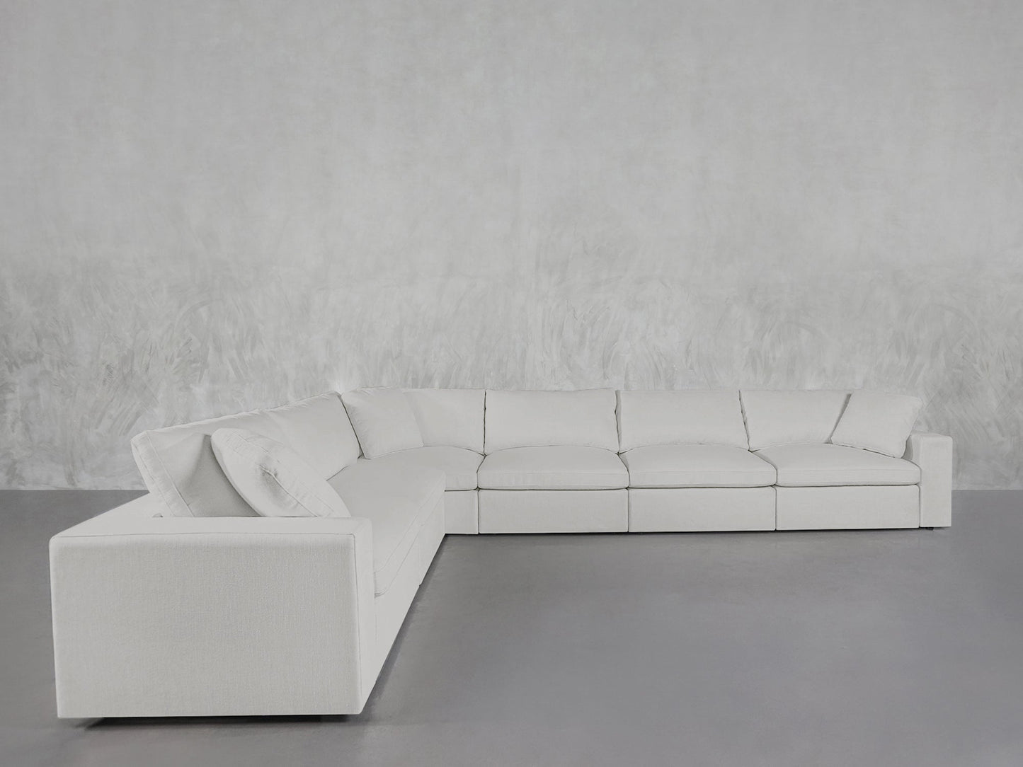 A 6-Seat Modular Corner Sectional with modern design and clean lines is set in a minimalistic room featuring a light gray floor and textured pale gray wall.