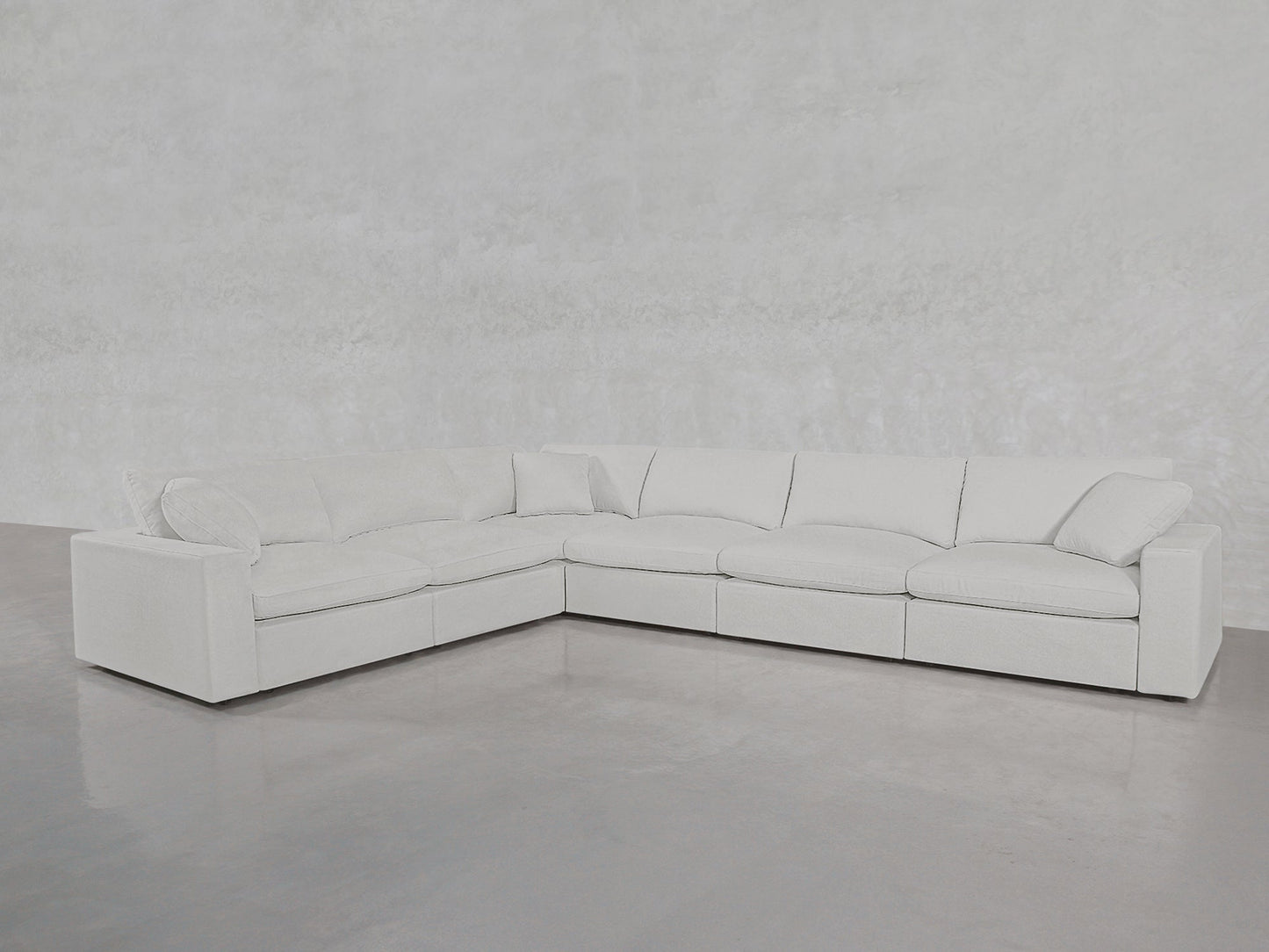 The 6-Seat Modular Corner Sectional, featuring plush cushions in white, sits on a smooth gray floor against a light textured wall in a minimalist, modern space.