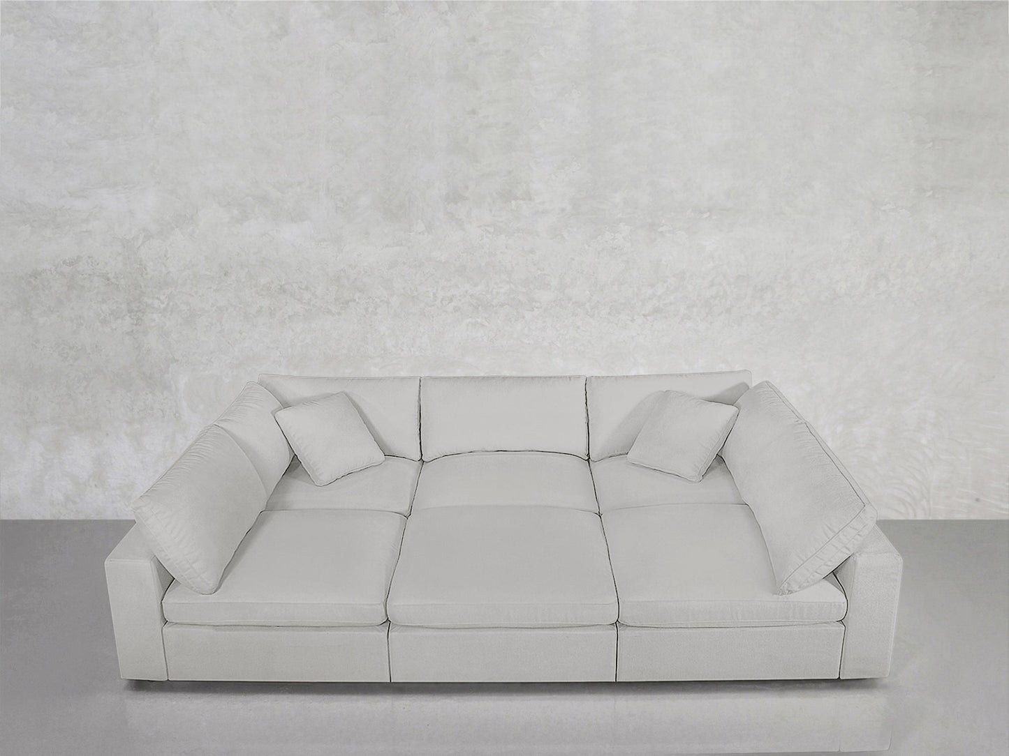The 6-Seat Modular Pit, in modern light gray, features three seat cushions and three matching pillows, set against a textured light gray wall and gray floor for a minimalist, monochromatic aesthetic.