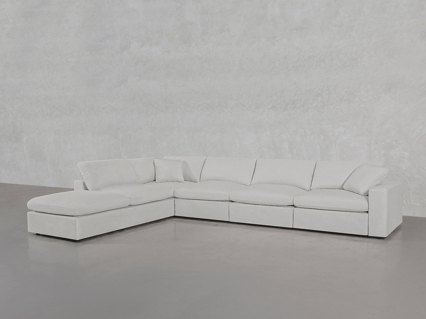 A spacious, modern 6-Seat Modular Corner Lounger Sectional in light gray with plush cushions and a left-side chaise is set against smooth, light-colored walls and flooring.
