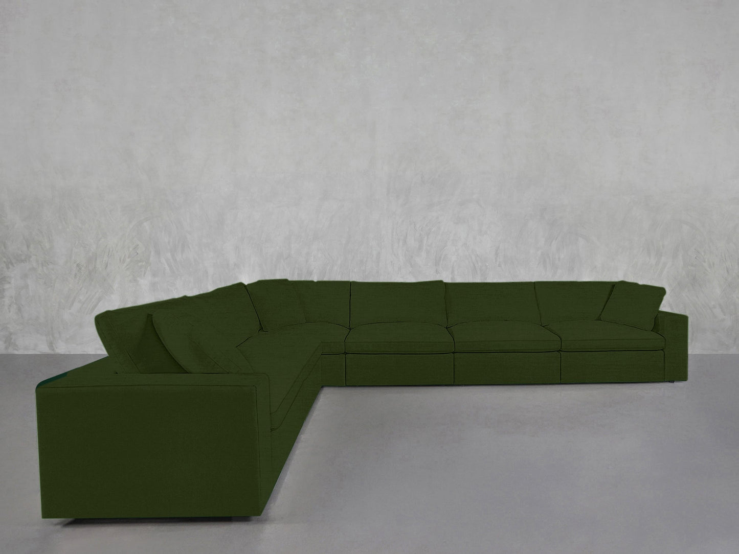A 6-Seat Modular Corner Sectional upholstered in dark green fabric is arranged in an L-shape against a light gray textured wall and floor.