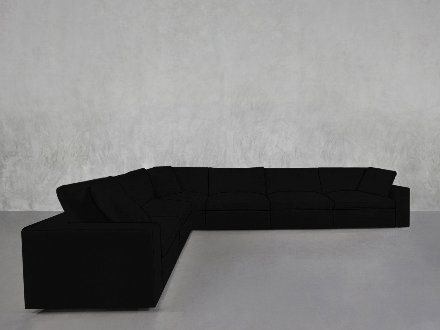 A 6-Seat Modular Corner Sectional with a modern black design and clean lines is arranged in an L-shape against a light gray textured wall and matching gray floor.