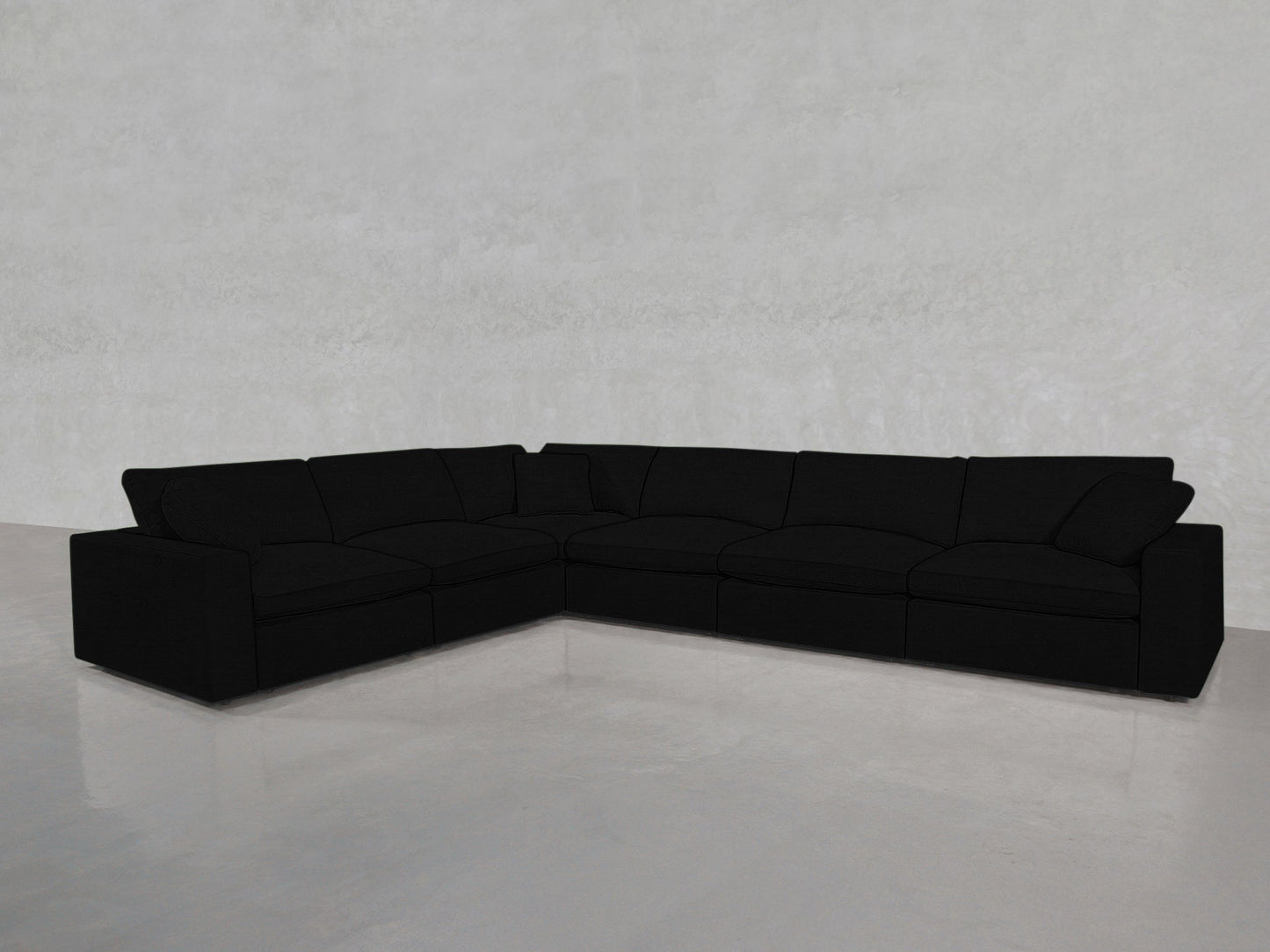A 6-Seat Modular Corner Sectional in black with wide cushions and armrests sits on a shiny, light gray floor against a textured pale gray wall.
