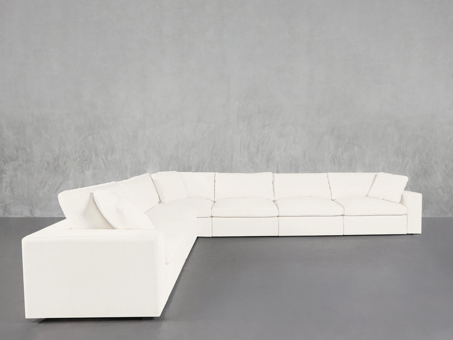 A 6-Seat Modular Corner Sectional with clean lines in white sits on a dark gray floor against a light gray textured wall.
