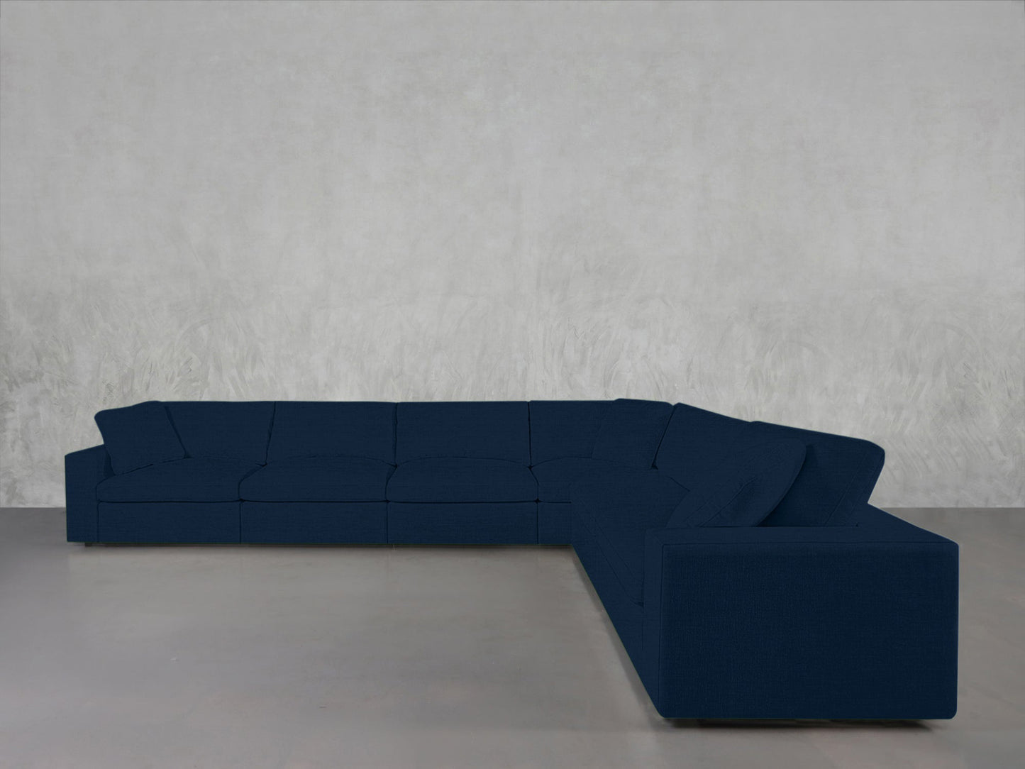 6-Seat Modular Corner Sectional in dark blue with clean lines, placed against a light gray textured wall and smooth gray floor.