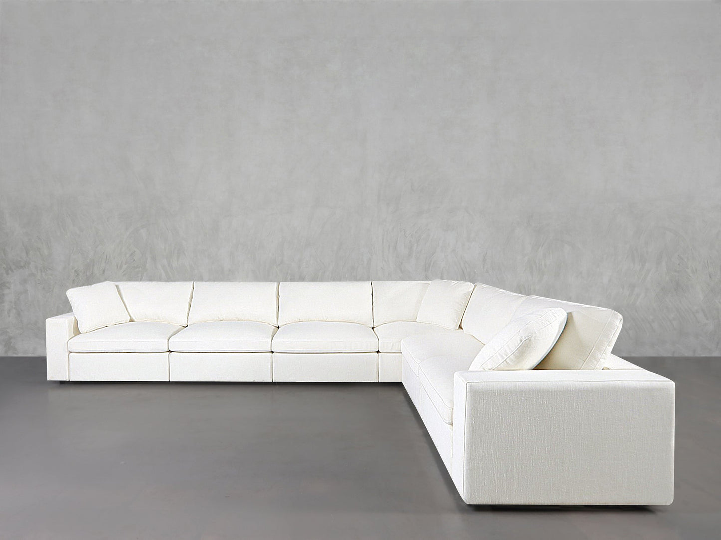 A 6-Seat Modular Corner Sectional in modern white with clean lines and plush cushions is set against a light gray wall on a gray floor.